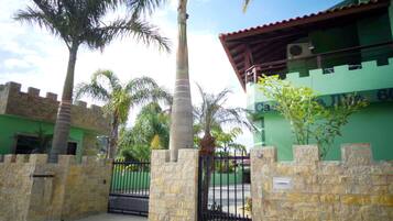 A building with a green facade, a stone wall, and a black gate.