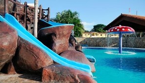 A water park with a blue slide, a mushroom-shaped water feature, and a pool.
