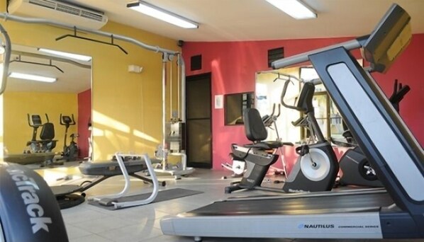 A gym with Nautilus commercial equipment, including treadmills and elliptical machines, with yellow and red walls.