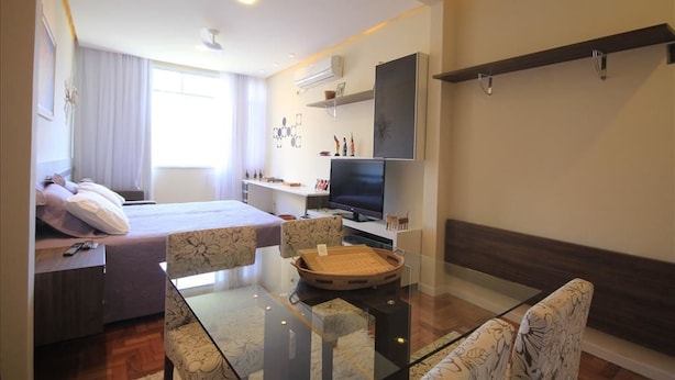 A modern hotel room with a bed, a TV, a dining area with a glass table, and a sofa. - Assis 801 (Rio de Janeiro)