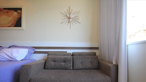 A room with a bed, a sofa, a wall decoration, and a window with curtains. - Assis 801 (Rio de Janeiro)