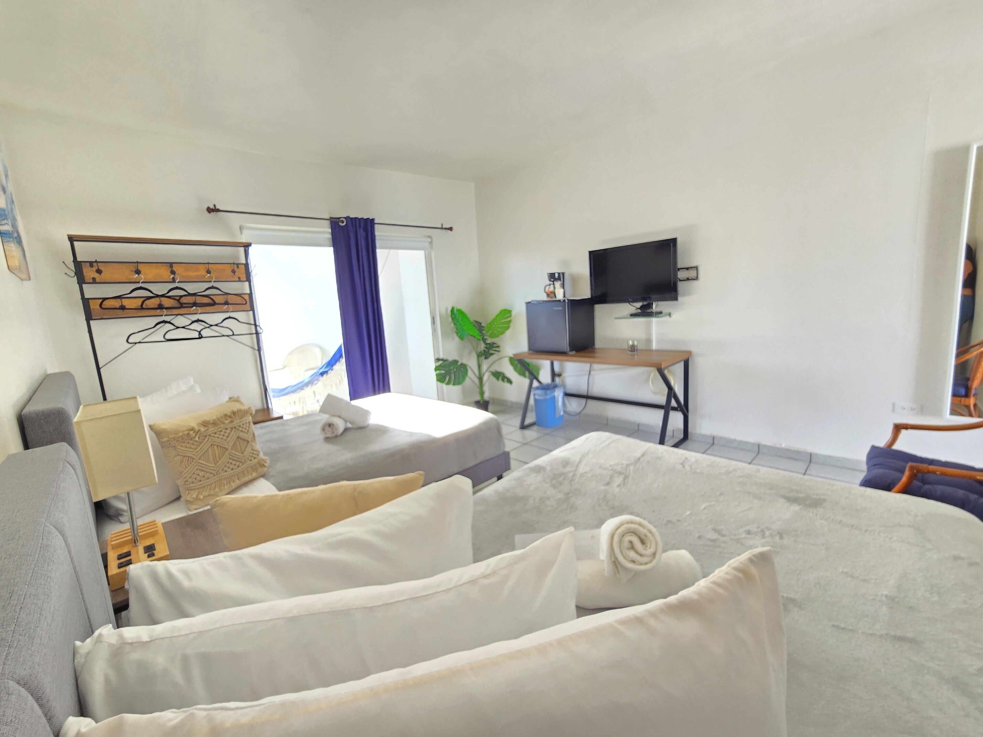 A hotel room with a bed, a desk, a TV, and a window with curtains.