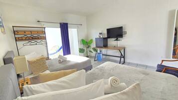 Quarto de hotel com cama, escrivaninha, televisão e janela com cortinas.