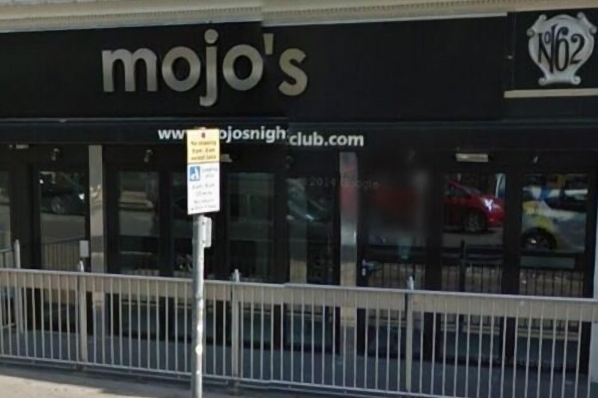 A storefront with the sign "mojo's" and a website address "www.mojosnightclub.com".