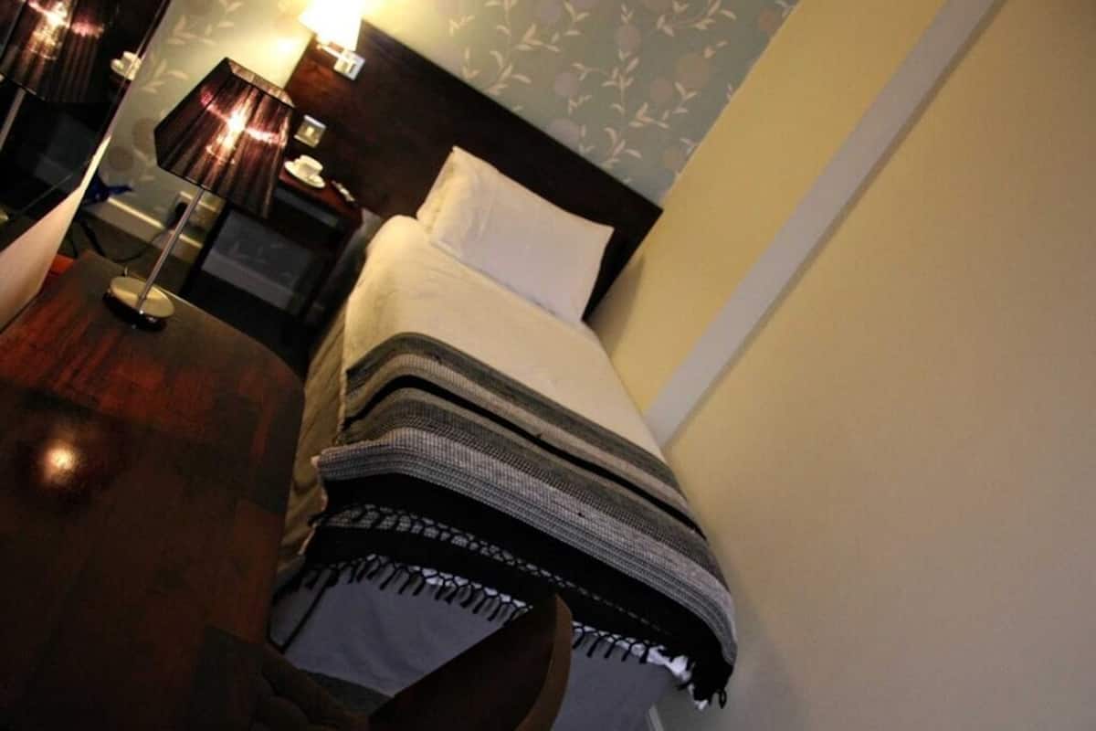 A hotel room with a bed, a nightstand, a lamp, and a mirror.