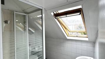 Un baño moderno con tragaluz, cabina de ducha de vidrio y lavabo.