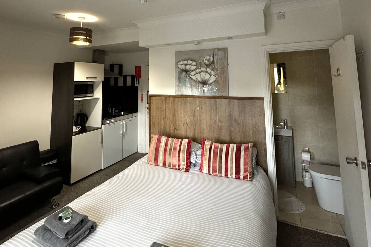 Une chambre d’hôtel comprenant un lit, un bureau, une kitchenette et une salle de bain.