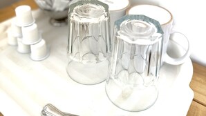 Un plateau avec des récipients en verre transparent et une tasse blanche posée sur une nappe blanche.