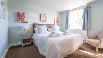 A hotel room with a large bed, a nightstand with a lamp, a chair, and artwork on the walls.