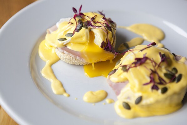 Un plato con huevos Benedict, adornado con semillas y brotes.