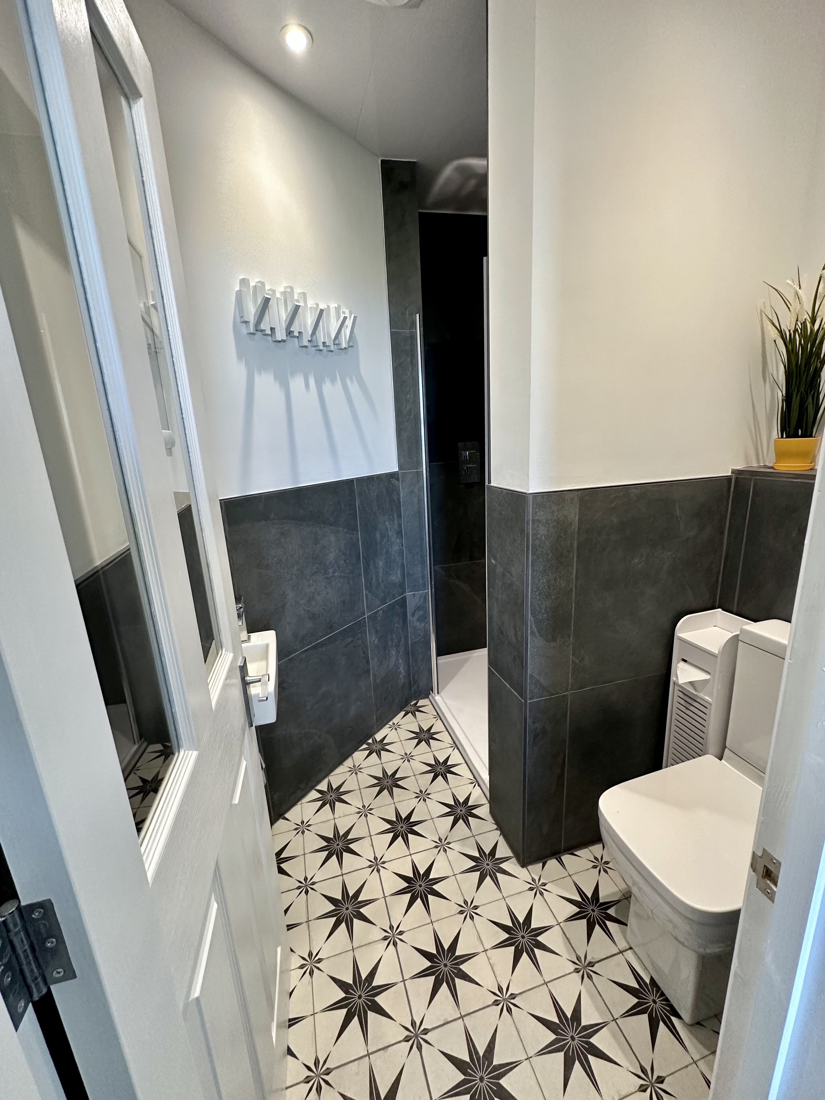 Ein modernes Badezimmer mit einem fußbodenhohen Sternenmuster, einer weißen Toilette und einer Duschkabine.