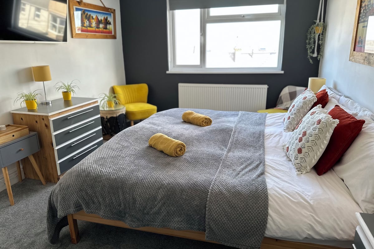 Une chambre à coucher avec un lit, un bureau, une chaise et une fenêtre.