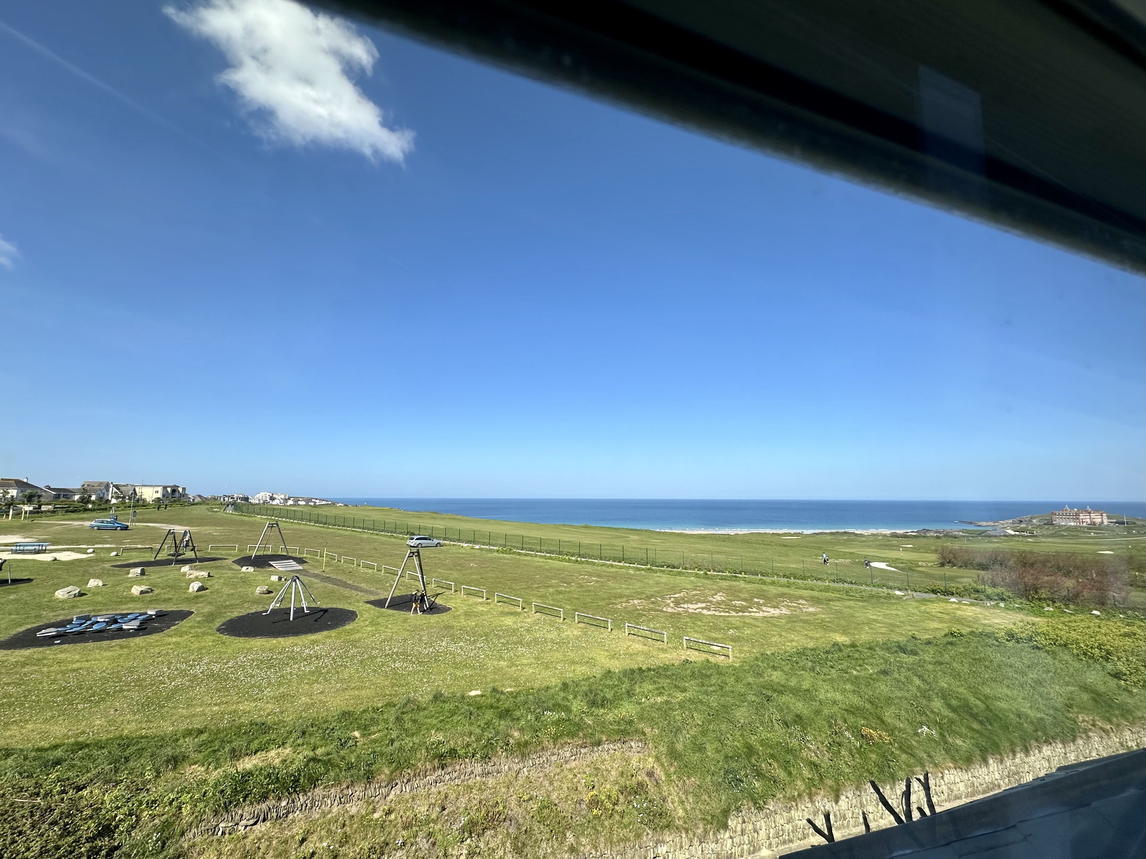 A golf course with bunkers, a water hazard, and a distant view of the ocean.