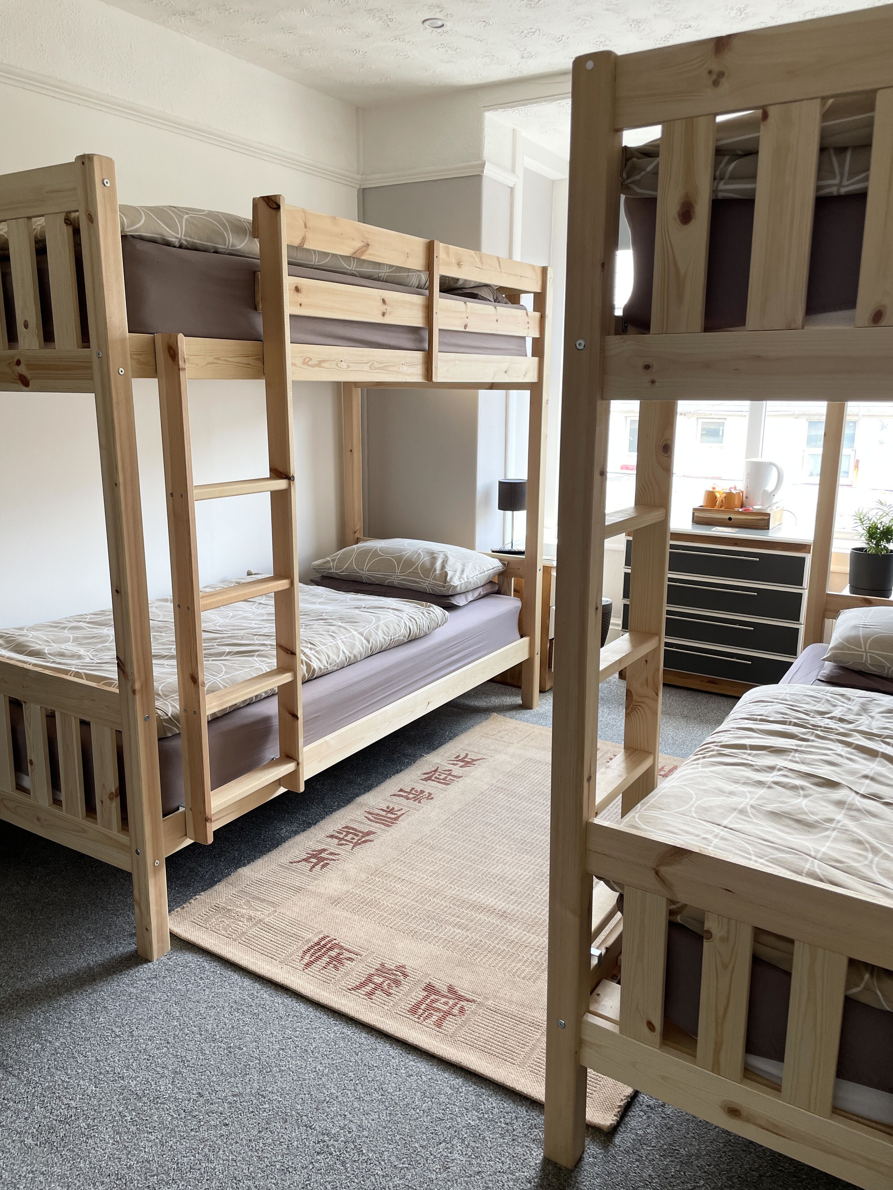 A bunk bed room with a window, a desk, and a rug.