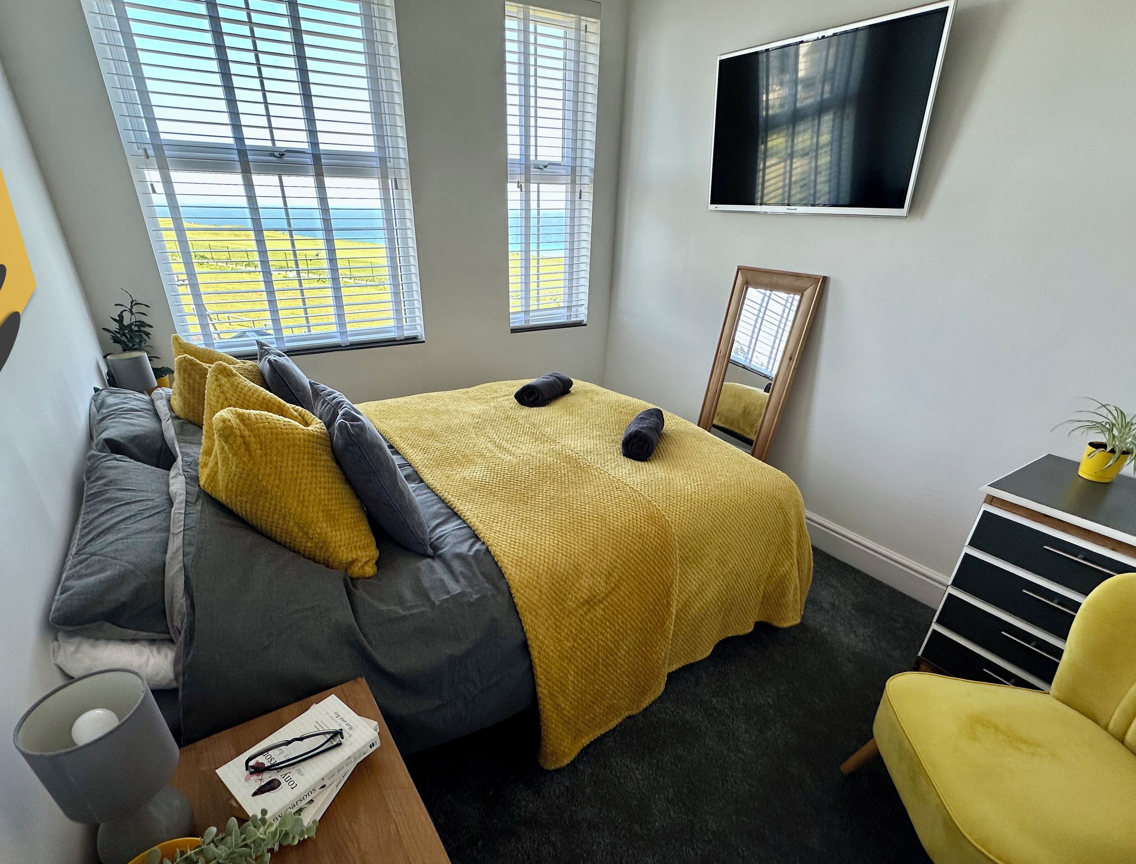 Um quarto moderno com cama, sofá, televisão e escrivaninha.