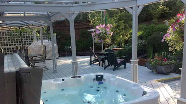 Un bain à remous situé dans un espace extérieur abrité, agrémenté d’une pergola, de sièges et de plantes en pot.