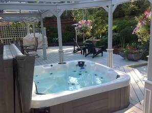 Ein Whirlpool in einem überdachten Außenbereich mit einer Pergola, Sitzgelegenheiten und Topfpflanzen.