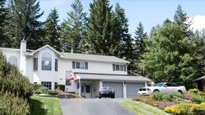 Une maison à deux étages avec un garage, une allée et un drapeau.