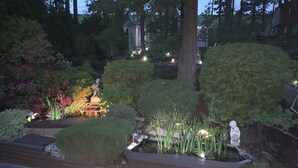 Un jardin avec un étang, un kiosque et diverses plantes.