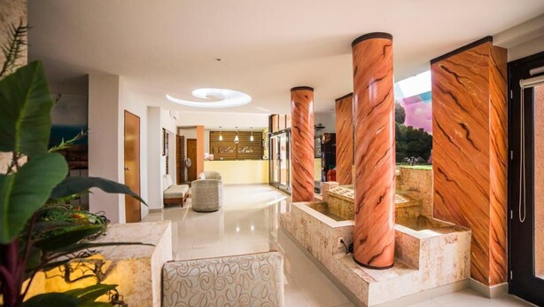 Um hall de hotel moderno com área de estar central, balcão de recepção e vista para o exterior.