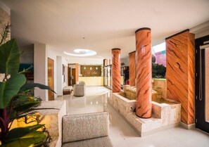 Een moderne hotel lobby met een centraal zitgedeelte, een receptiebalie en uitzicht op het buitengebied.