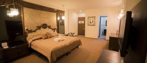 A spacious bedroom with a large bed, a television, and a desk.