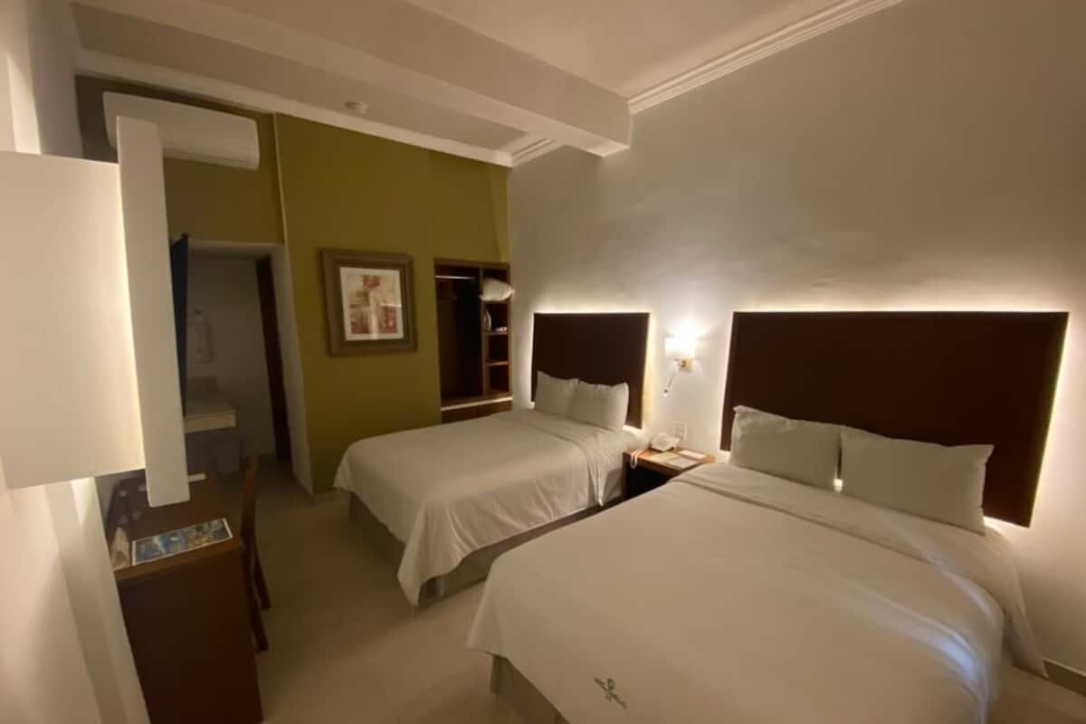 A hotel room with two beds, a desk, and a wardrobe.
