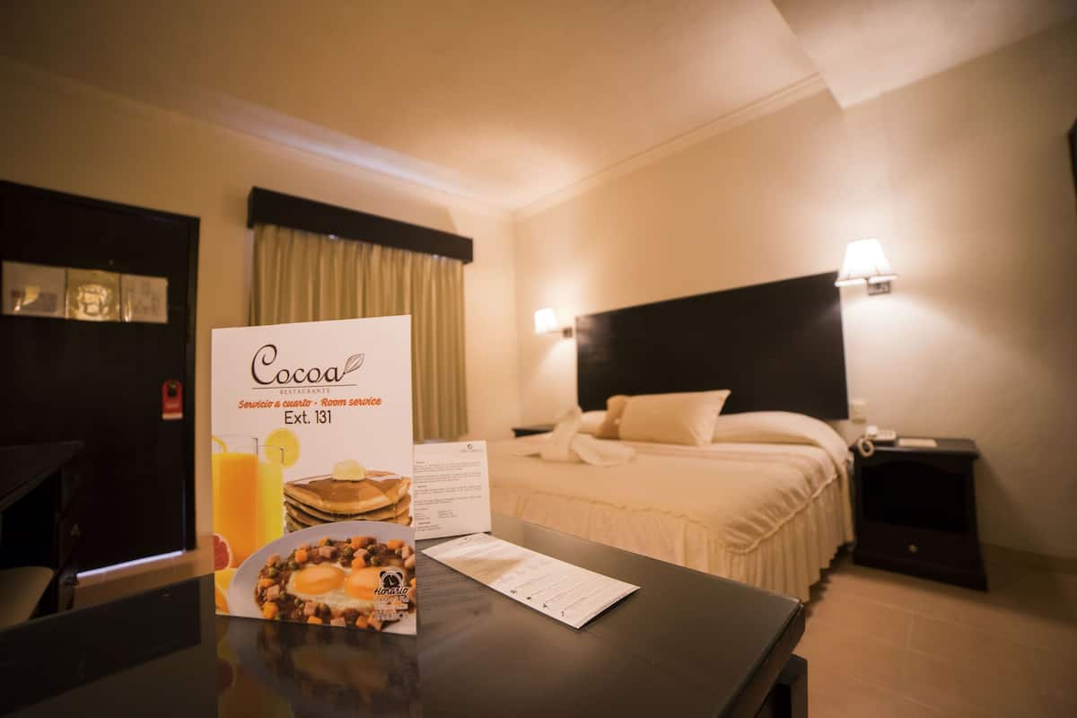 A hotel room with a bed, bedside lamps, a table with a menu, and a sign for a restaurant.