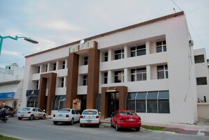 Hotel 'Hotel Marlon' con una fachada moderna, varios espacios de estacionamiento y una tienda llamada 'Cocoa'.