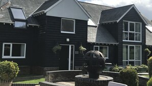 Ein schwarzes, zweistöckiges Haus mit einer großen, kugelförmigen Skulptur im Vorgarten.