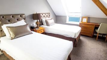 A bedroom with two beds, a desk, a chair, and a window with blinds.
