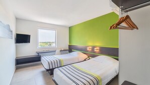 Een hotelkamer met twee bedden, een televisie, een raam en een groene accentmuur.
