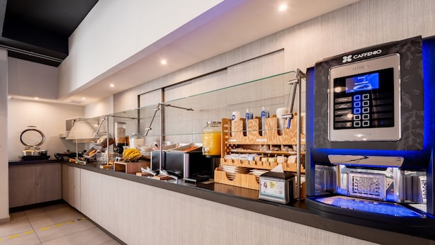 Een modern café met een zelfbedieningskoffieapparaat, diverse dranken en een presentatie van koffiebonen.
