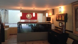 A modern living room with a pool table, a red accent wall, and a large window.