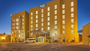 A CityExpress hotel with a modern design, featuring a large parking area and a van in front.