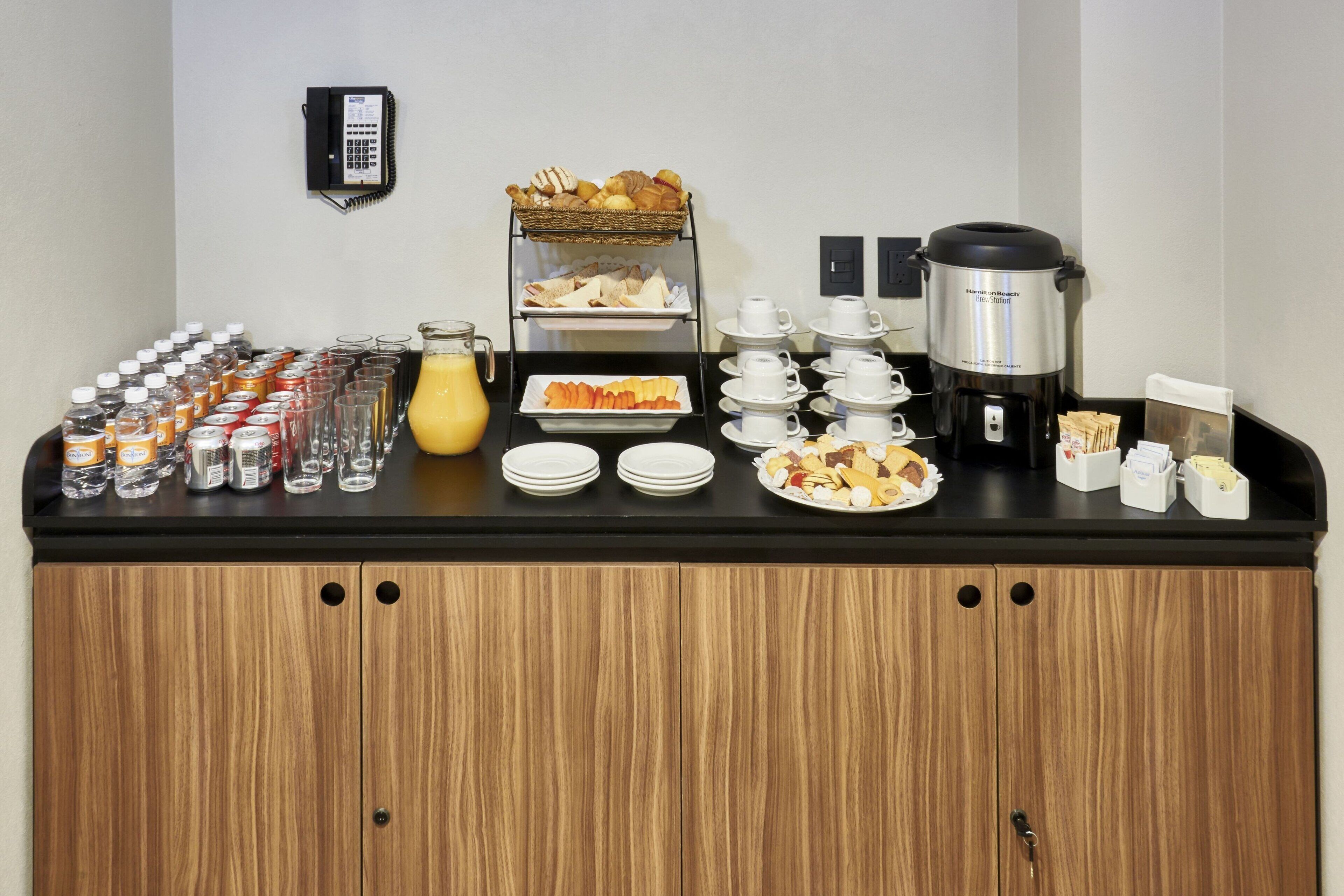 Disposição de buffet com diversos alimentos, uma máquina de café e um dispensador de água.