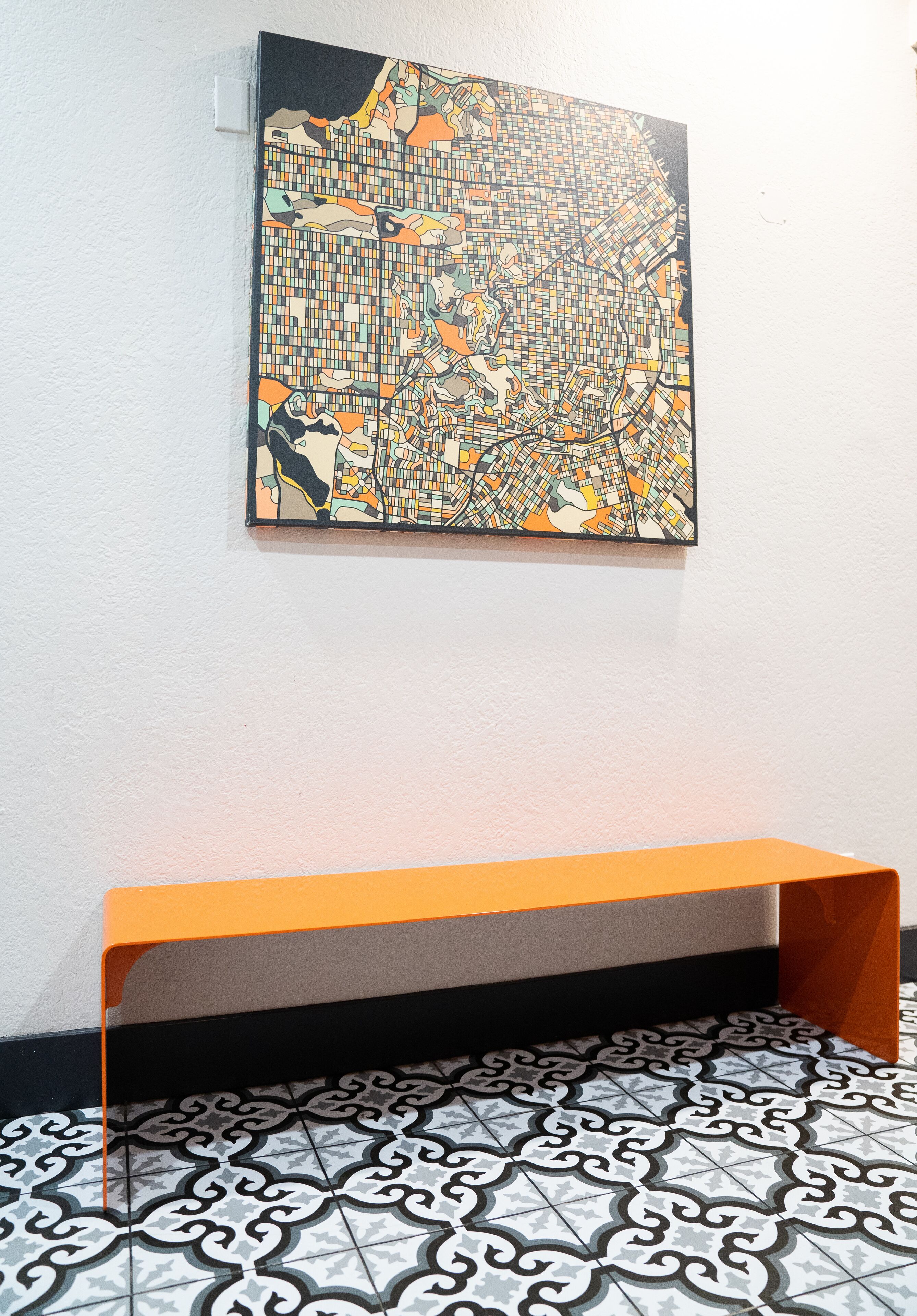 A room with a tiled floor, a bench, and a wall-mounted artwork.
