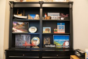 A display cabinet with various travel memorabilia, including a model ship, postcards, and a sign for San Francisco. - Amsterdam Hostel (San Francisco)