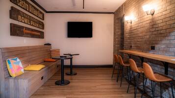 A restaurant interior with a wooden bench seating area, a bar counter with stools, and a flat-screen TV mounted on the wall.