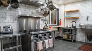 A modern kitchen with stainless steel appliances, a gas stove, a microwave, and a coffee machine. - Amsterdam Hostel (San Francisco)