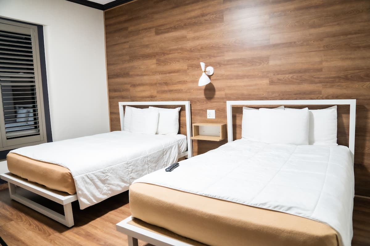 Two single beds with white bedding and a wooden wall panel.