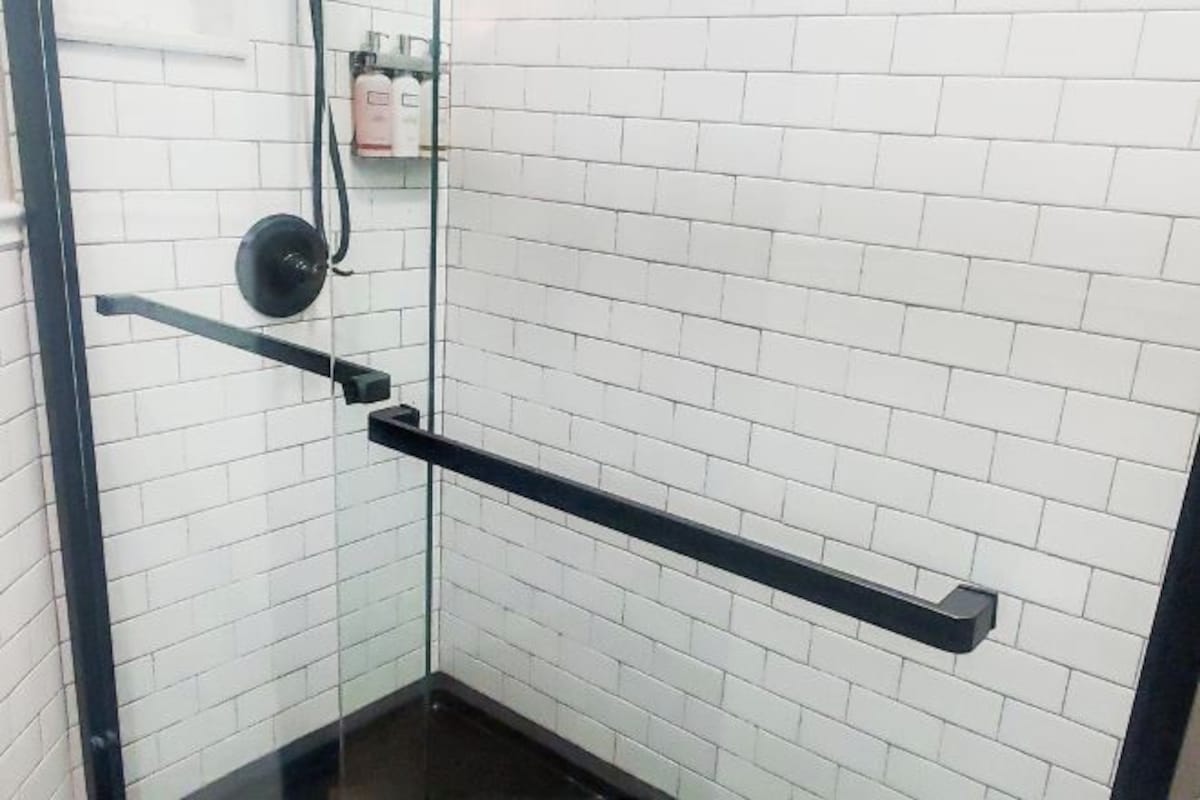 A corner of a room with white tiled walls and a glass door.