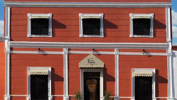 A red building with three windows and a central entrance with a sign reading "Hotel del Erigro".