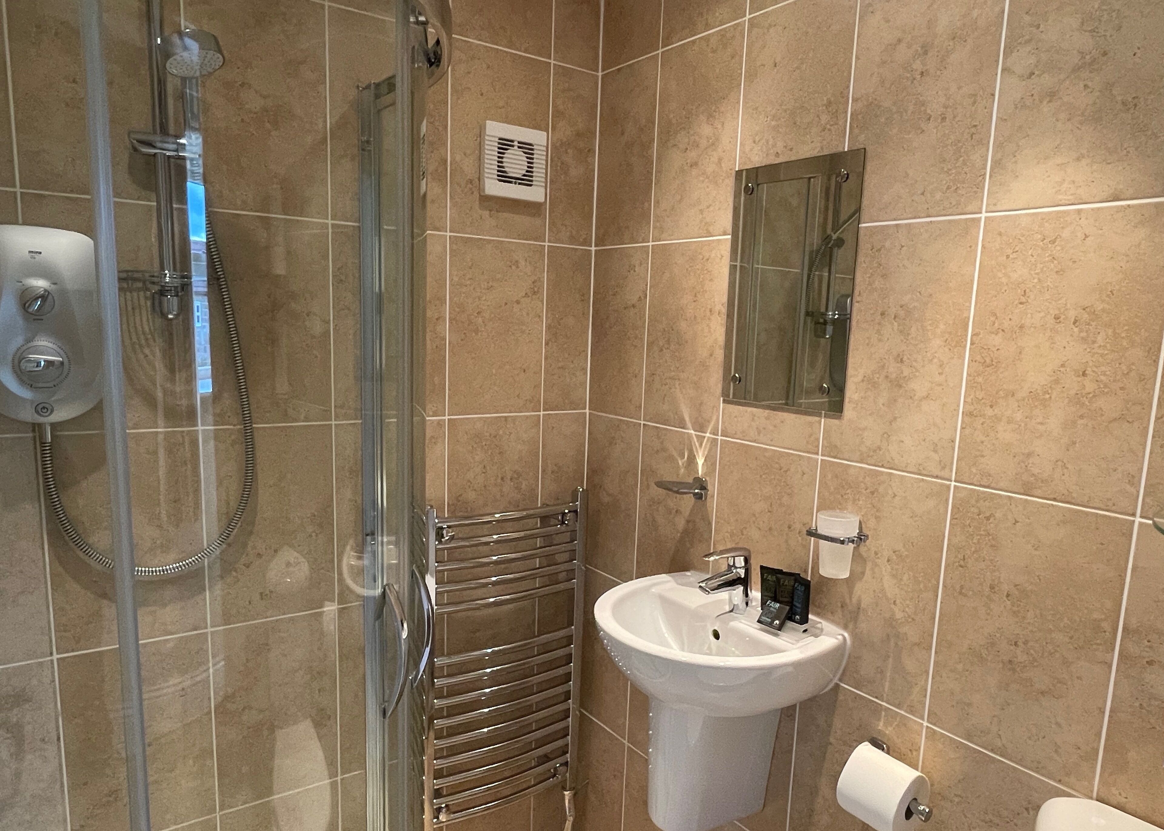 Une salle de bain avec une douche à parois de verre, un lavabo blanc et des toilettes.