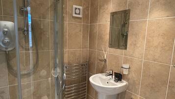 A bathroom with a glass-enclosed shower, a white sink, and a toilet.