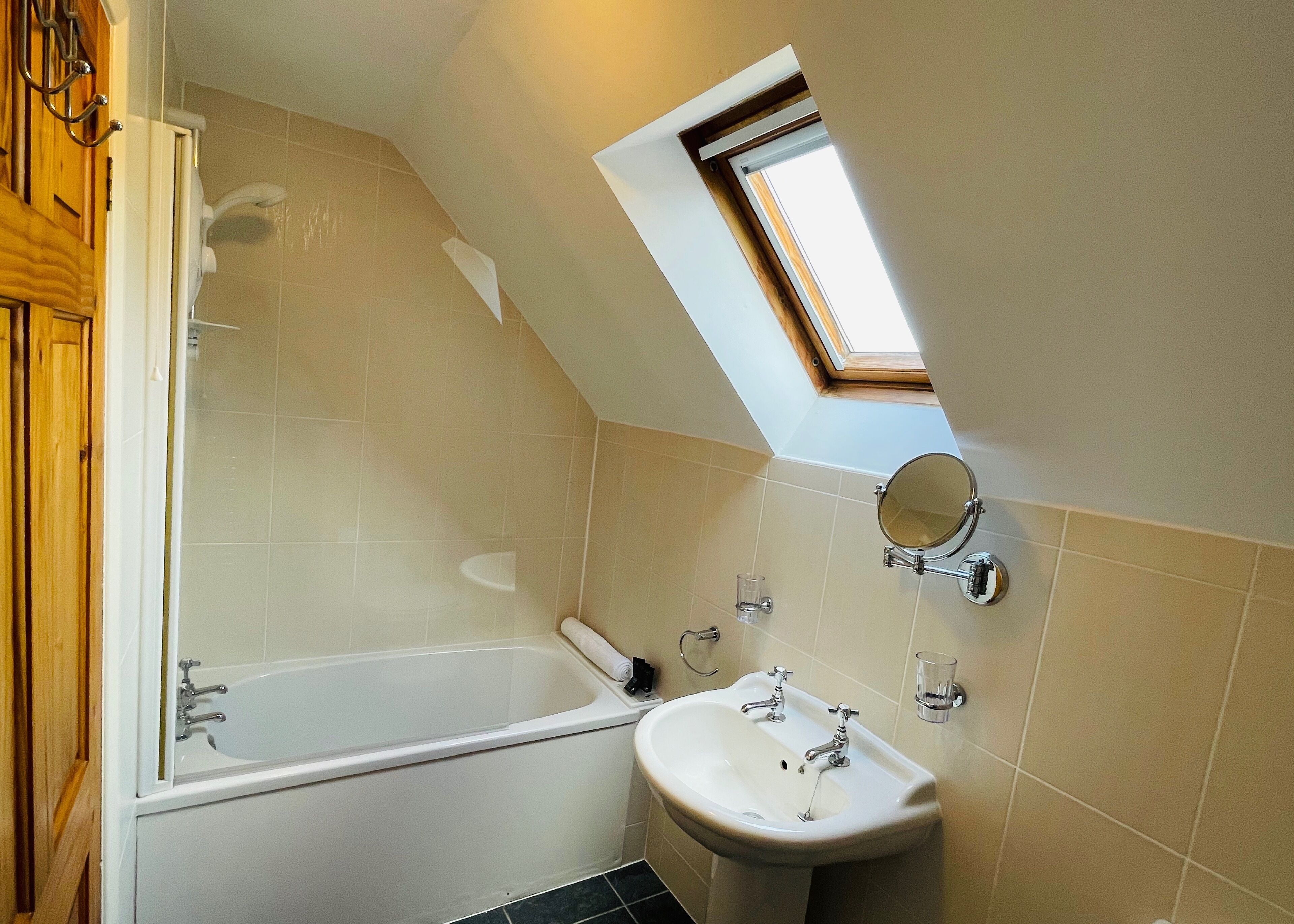 A bathroom with a bathtub, a sink, a mirror, and a skylight.