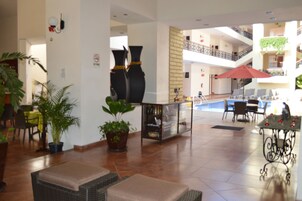 Un vestíbulo amplio con zona de piscina, áreas de descanso y plantas en macetas.