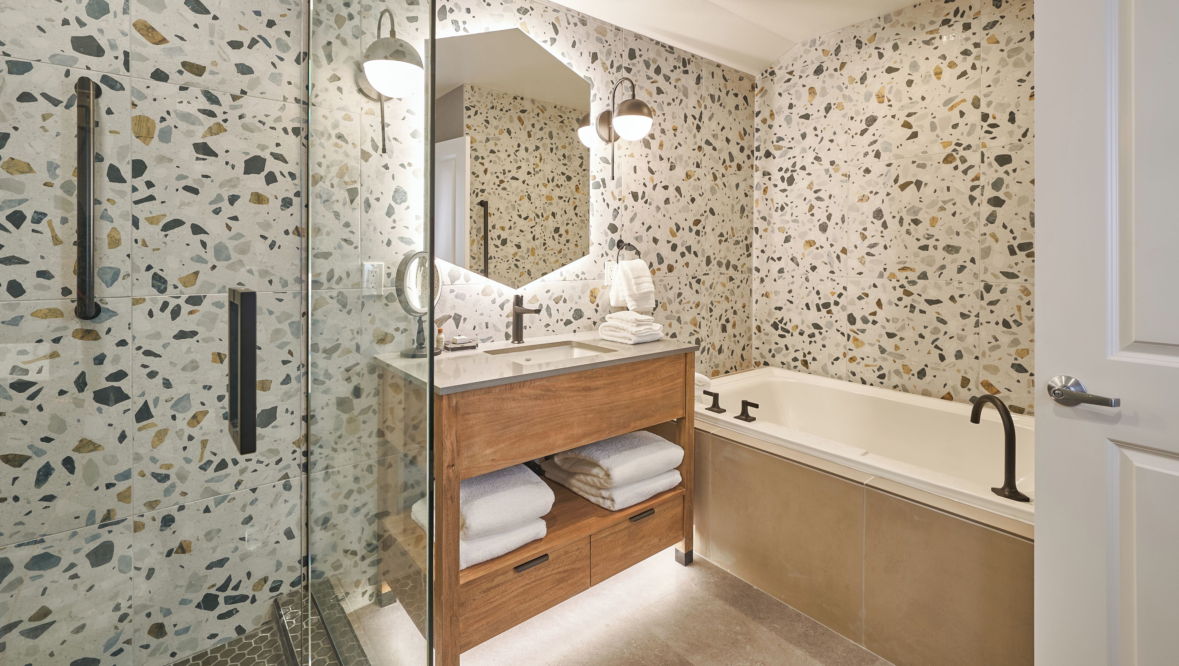 A modern bathroom with a freestanding bathtub, a wooden vanity with a mirror, and a glass shower enclosure.