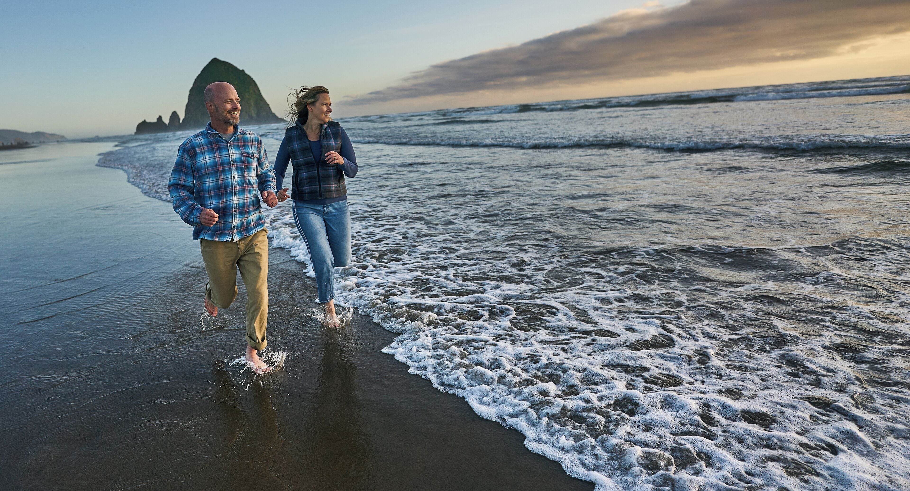 Dos personas caminando por la playa con olas.
