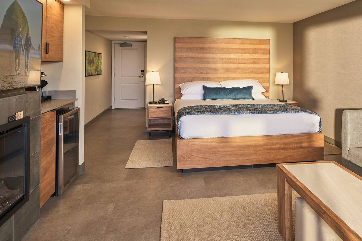 A hotel room with a bed, a sofa, a TV, a desk, and a door.